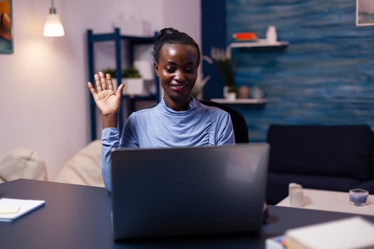 African businesswoman greeting people during conference late at night in home office. Black freelancer working with remotely team chatting virtual online conference. photo