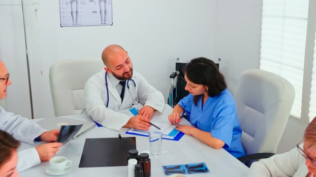 Medical expert talking with medical staff during healthcare meeting in hospital conference room explaining radiographys. Clinic therapist talking with colleagues about disease, medicine professional photo
