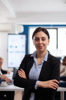 Woman entrepreneur smiling at camera standing in conference room, preparing for meeting with partners. Manager working in professional start up financial business, modern company workplace ready for meeting. photo