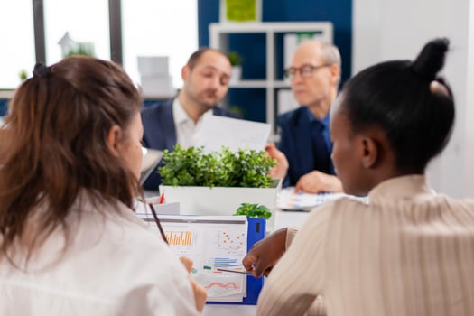 Focused mixraced professional team business people work together at meeting table. Multiethnic colleagues working planning success financial strategy discussing in office. photo