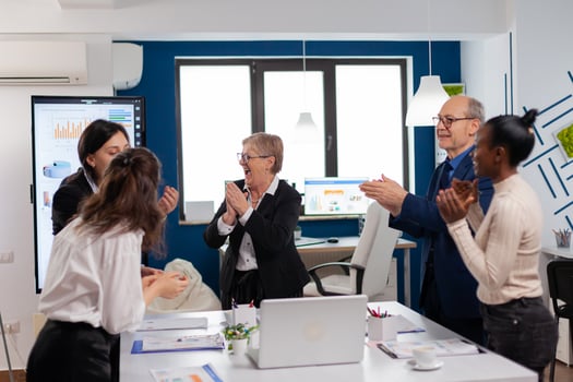 Victorious overjoyed diverse team of businesspeople clapping together in conference room. Multiethnical partners coworkers celebrate successful teamwork result at company briefing photo