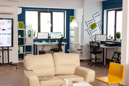 Interior of empty creative office with dusky light, new business, start up company with no people in it. Modern design and confortable couch with nobody in it, place of work startup photo