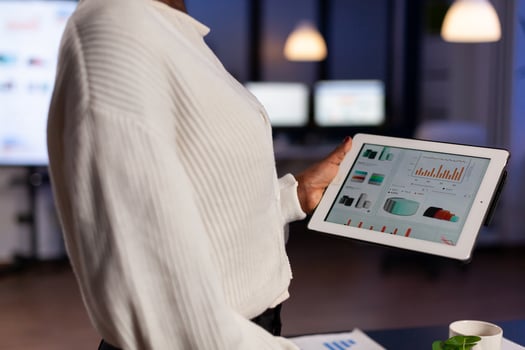 Close up of black entrepreneur analysing financial reports on tablet pc standing in start up office. Busy african employee analysing financial statistics in workplace overworking writing, searching. photo