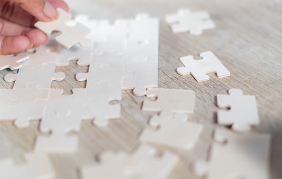 Hand holding piece of blank jigsaw puzzle photo