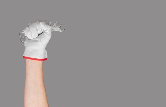 Hand with spanner in white glove. Work background with house and wall equipment. Hygiene and photo
