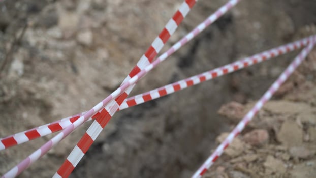 Red white barrier tape trenches. Focus on red and white barrier tape at construction site. Ribbons indicate dug trenches. photo