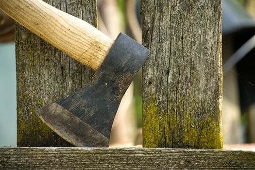Detailed depiction of an axe embedded in an aged, weather wooden fence photo