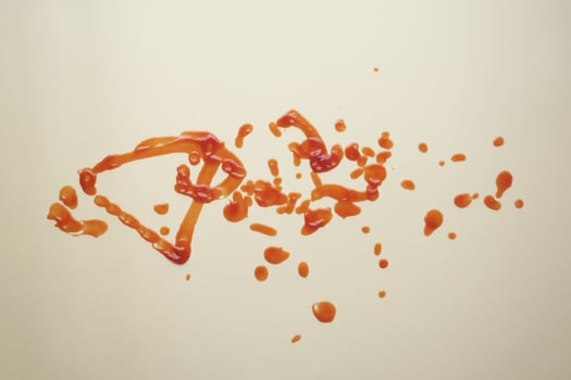 red ketchup splashes on purple background, tomato puree texture. photo