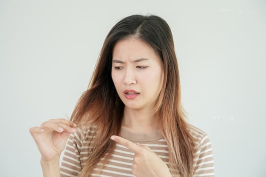 Asian woman very sad and upset looking at damaged hair, hair loss, hair thinning problem, vitamin deficiency, baldness, postpartum, biotin, zinc, menstrual or endocrine disorders, hormonal imbalance photo