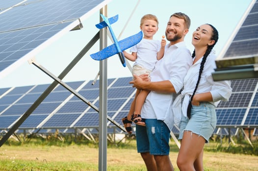 Young family of three is crouching near photovoltaic solar panel, little boy and parents. modern family concept. The concept of green energy photo