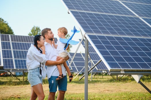 Young family with a small child in her arms on a background of solar panels. A man and a woman look at each other with love. Solar energy concept. photo