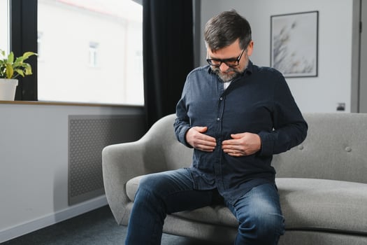 Senior man is suffering from problems with a digestion at home photo