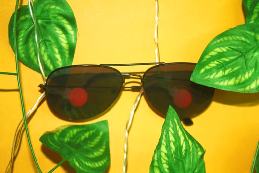 A pair of glasses suspended from a cable, decorated with leaves, and set against a yellow background. photo