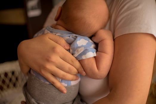 Loving mom carying of her newborn baby at home. Cute candid portrait of happy mum holding sleeping infant child on hands. Mother hugging her little 2 months old daughter. photo
