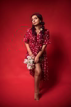 beautiful girl in a red dress on a red background with flowers photo