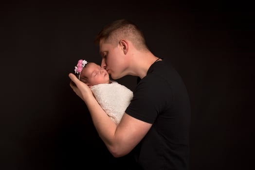 Red-haired father and newborn daughter on a black background. photo