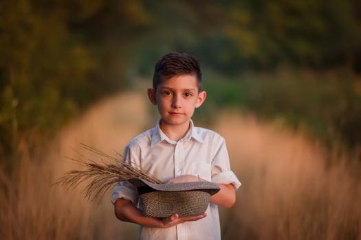 handsome boy in a hat sits on a country road photo