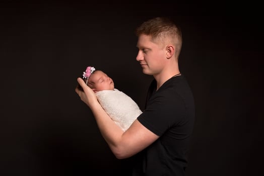 Red-haired father and newborn daughter on a black background. photo