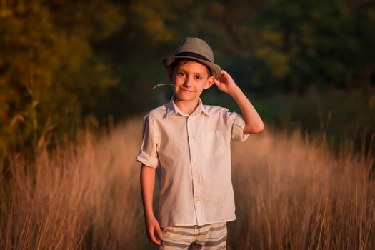 handsome boy in a hat sits on a country road photo