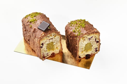 Sliced fruitcake with dried berries, milk chocolate glaze and pistachio photo