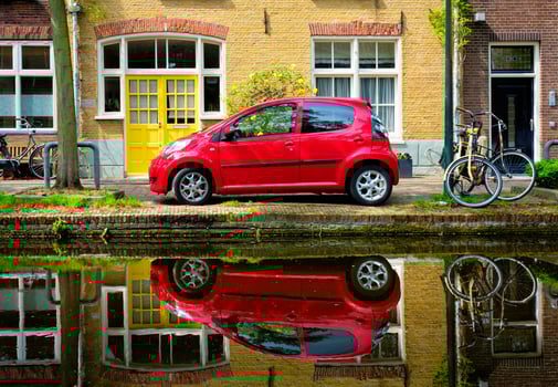 Red car on canal embankment in street of Delft. Delft, Netherlands photo