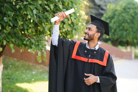 Portrait of indian handsome male graduate in graduation robe. photo