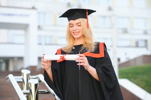 Portrait enthusiastic female college student graduate in cap and gown celebrating, holding diploma. photo