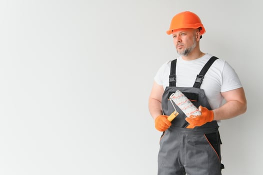 Painter using a paint roller and painting a wall isolated on white background. photo