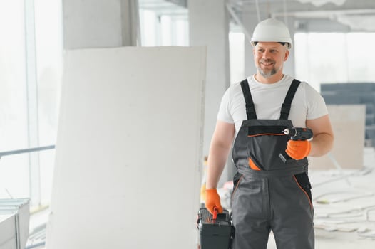 A man with a beard in a helmet and work clothes. Portrait of a worker in workwear with copy space. photo