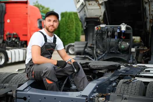 Semi Truck Under Maintenance. Caucasian Truck Mechanic Working to Fix the Tractor. photo