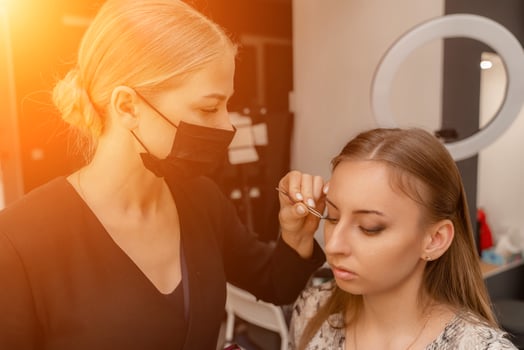 Makeup artist paints eyelashes to a woman in a beauty salon. photo