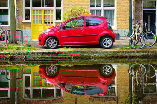 Red car on canal embankment in street of Delft. Delft, Netherlands photo