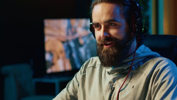 Smiling gamer discussing with teammates while playing competitive esports tournament. Happy man enjoying time spent together with friends in multiplayer videogame, chatting through headset mic photo