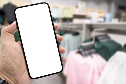 Hand holding blank screen smartphone for copy space on blurred clothing store. e-commerce app shopping mockup. social media, payment and shopping online concept. fashion and technology. photo