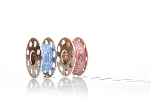 spools of blue and pink thread on a white background photo