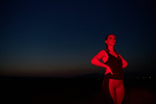 Athlete Strikes a Pose in Red-Lit Nighttime Glow photo