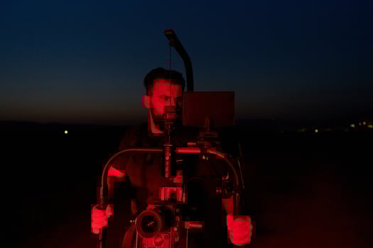 Nighttime Capture. Professional Videographer Films Athletes Running in Red-Lit Darkness photo