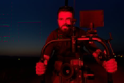 Nighttime Capture. Professional Videographer Films Athletes Running in Red-Lit Darkness photo