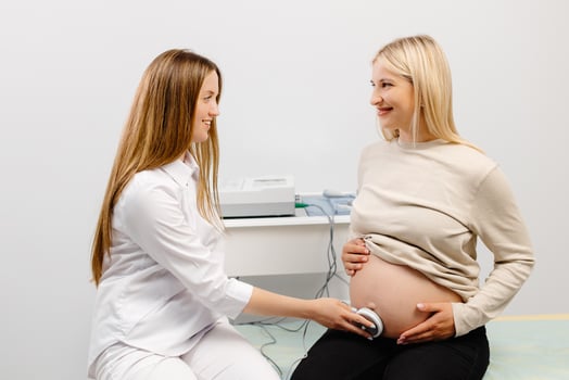 Doctor prepares a pregnant woman for checking fetal heartbeat by fetal monitoring. photo