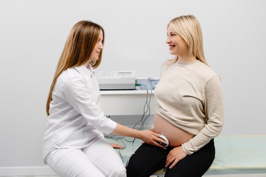 Doctor prepares a pregnant woman for checking fetal heartbeat by fetal monitoring. photo
