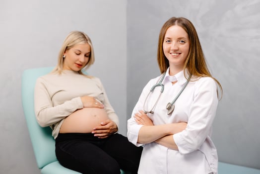 Gynecologist preparing for an examination procedure for a pregnant woman sitting on a gynecological chair in the office and smiling photo