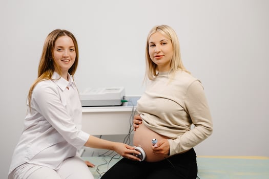 Doctor prepares a pregnant woman for checking fetal heartbeat by fetal monitoring. photo