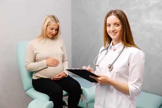 Gynecologist talking with a young female patient during a medical consultation in the gynecological office and and making entries in the patient's medical record photo