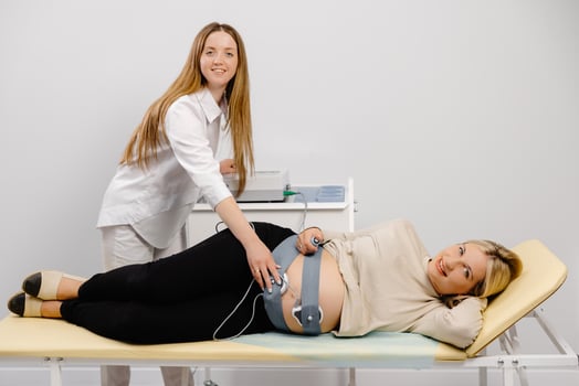 Doctor prepares a pregnant woman for checking fetal heartbeat by fetal monitoring. photo