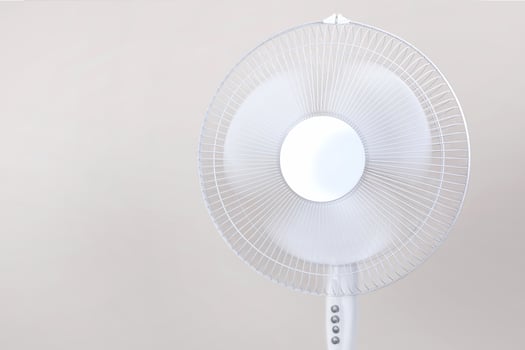Electric Floor fan turned on white isolated on beige background. Relief from the heat, hot summer. Close up photo