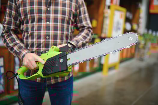 Worke holds electric saw in tool store photo