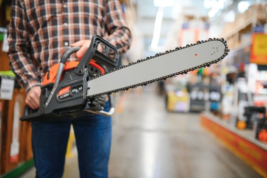 Worke holds electric saw in tool store photo