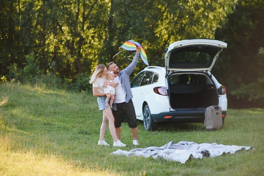 Happy family near car trunk on sunny day. Road trip photo