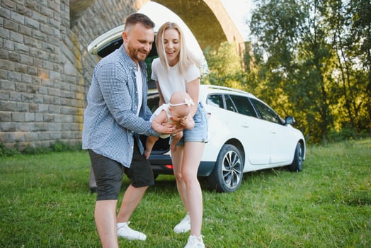 Young family three people in white clothes have picnic. Beautiful parents and daughter travel by car during summer vacation. Scene in park photo
