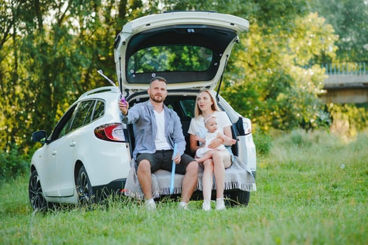 Happy family near car trunk on sunny day. Road trip photo